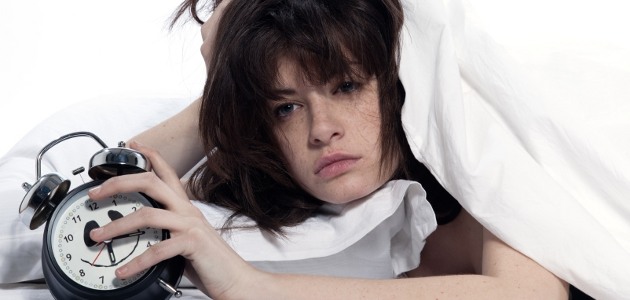 fille dans un lit qui tient un réveil